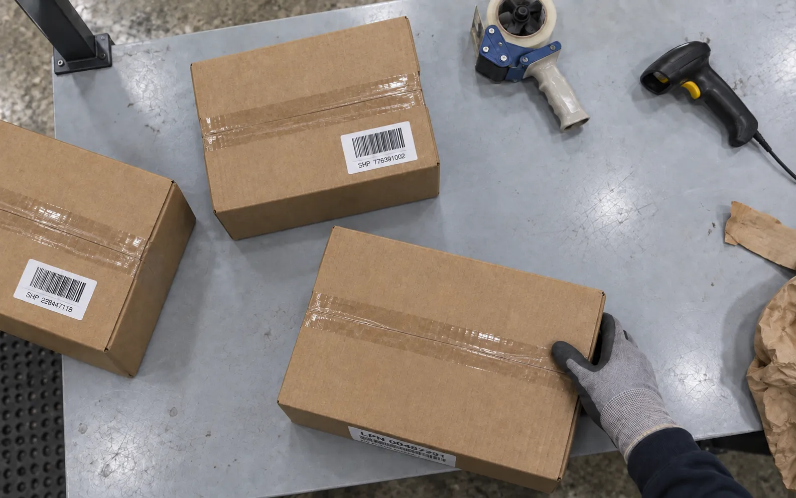 Camera mounted beneath the packing bench’s overhead task light looking down at unevenly placed cartons as an operator handles the order.